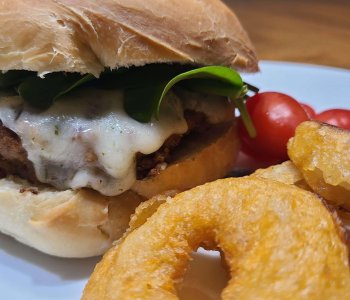 Homemade burger with melted mozzarella on a bun.